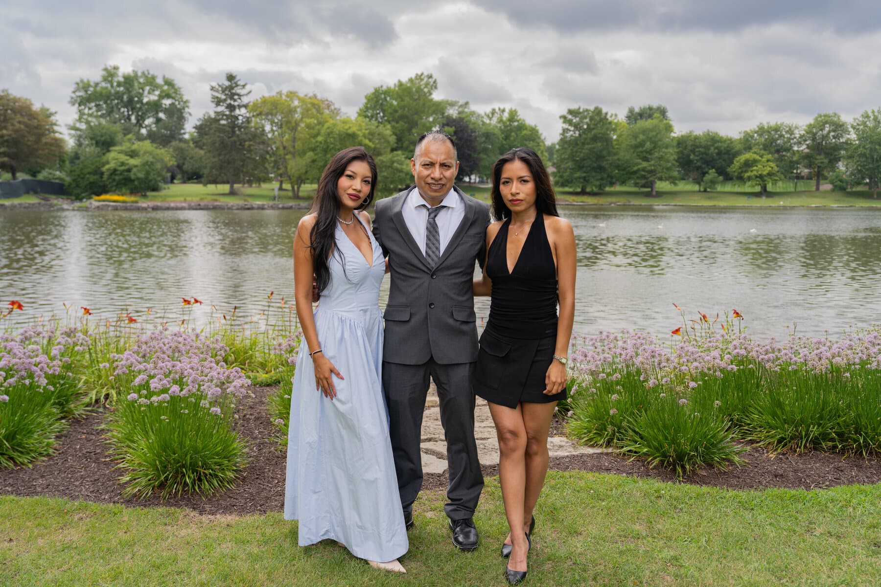 Family portrait of a father and his two daughters by a park lake