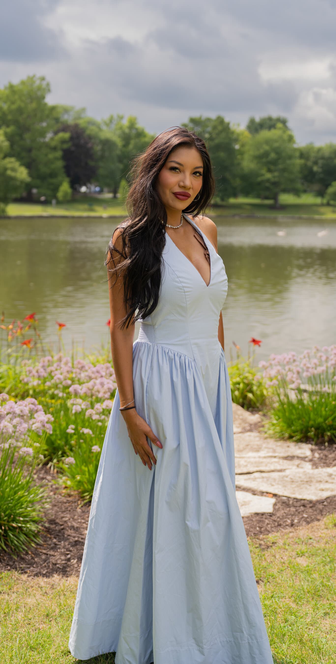 Portrait of a young woman in a light blue dress by a park lake