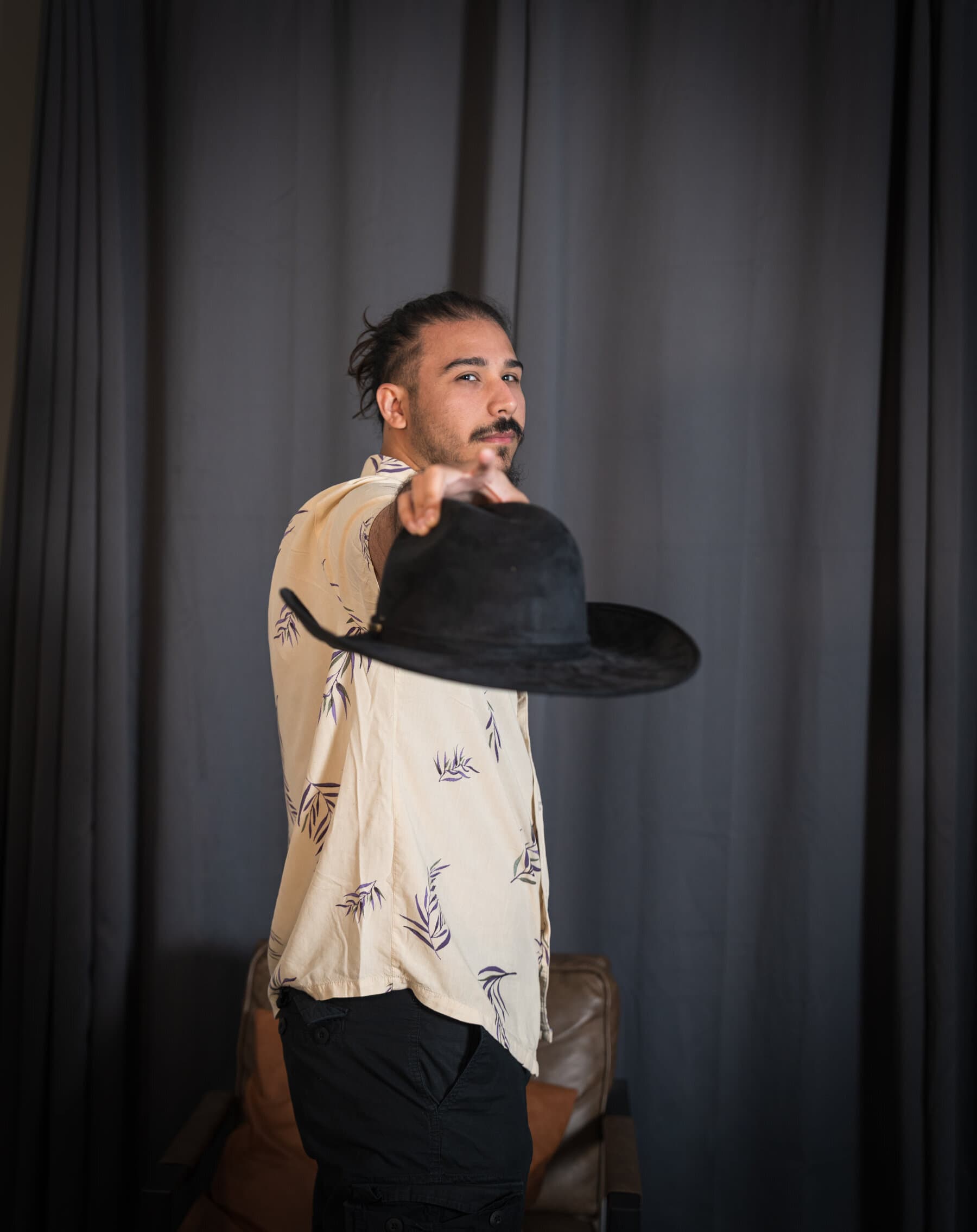 Portrait of a man tossing his cowboy hat toward the camera, studio backdrop