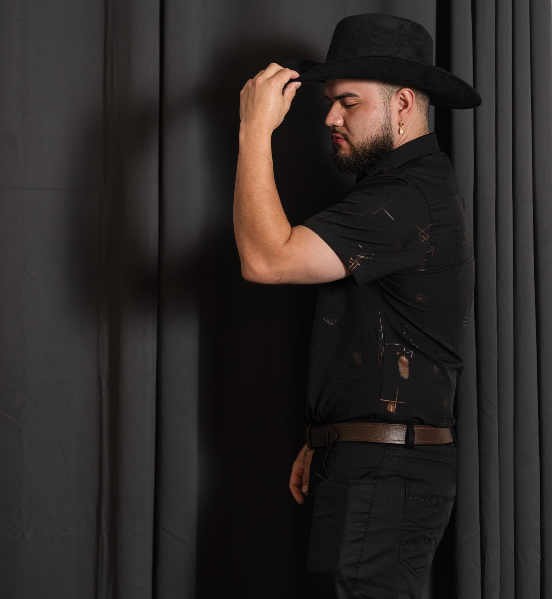 Portrait of a man tipping his cowboy hat, studio backdrop